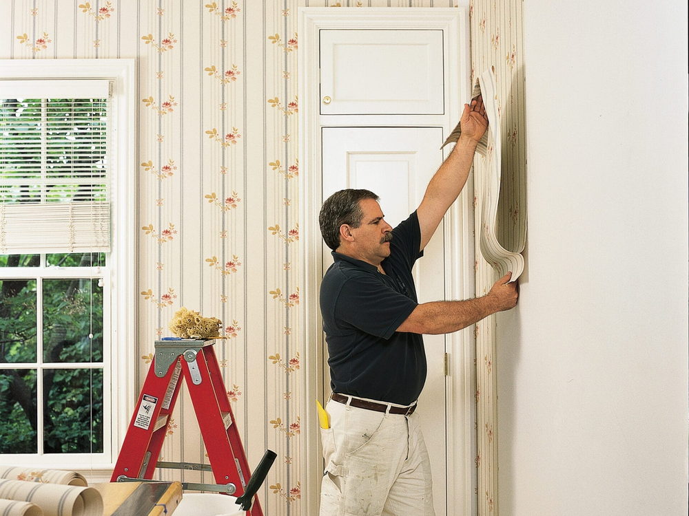 Wallpaper installer carefully pushing a patterned wallpaper panel into place beside a door frame